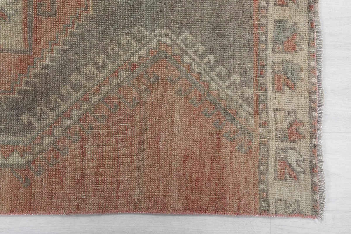 Close-up of the rust field and the edge of a gray geometric medallion, showing the faded colors