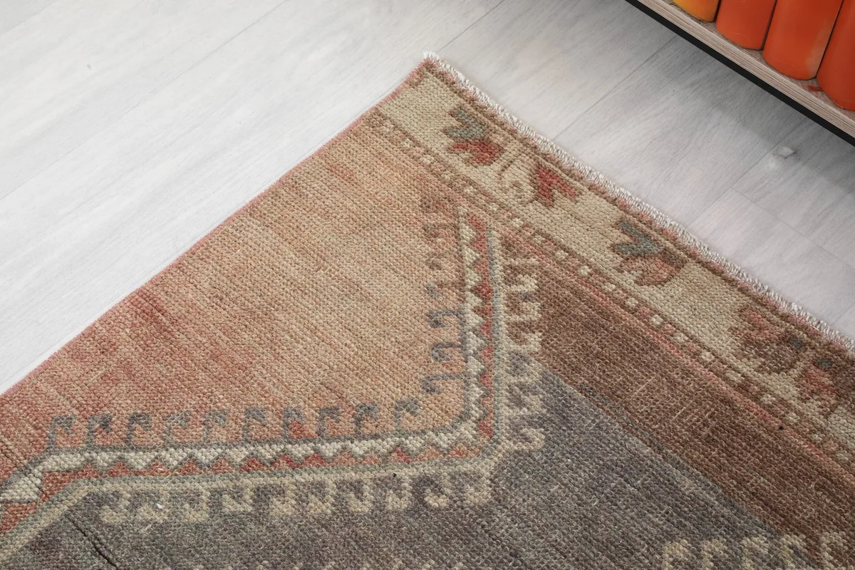 Close-up of the rug's border design featuring small floral or geometric elements in beige and rust