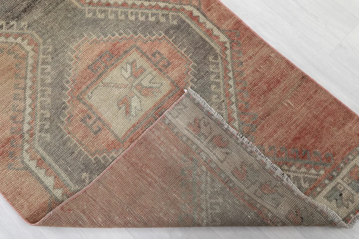 Corner of the rug folded back, revealing the cotton foundation and the reverse side of the knots