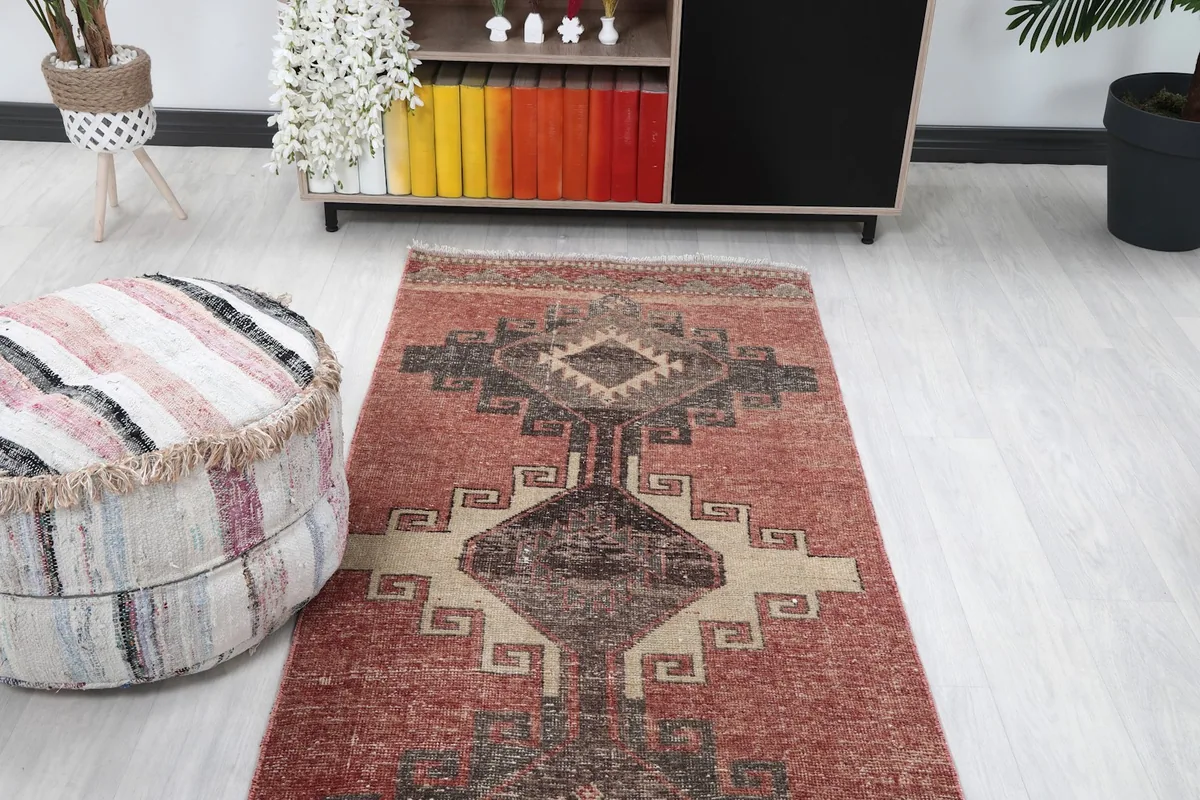View from above the rug's upper section, showing the patterns extending towards the end and a nearby ottoman.