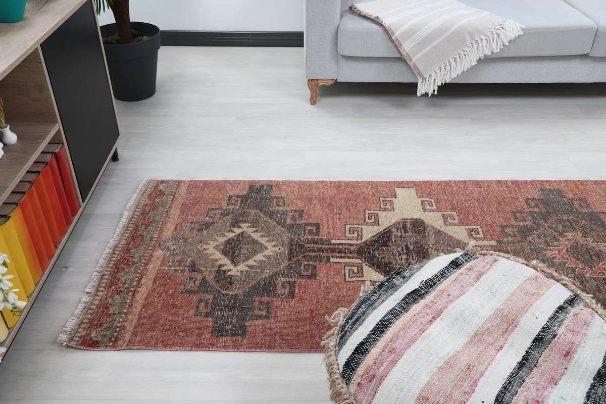 Runner rug positioned in a room, capturing its length and visual impact alongside a sofa and shelf.