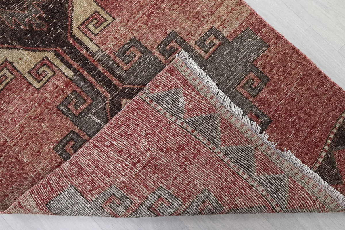 Corner of the rug folded back, revealing the reverse side of the hand-knotted cotton foundation.