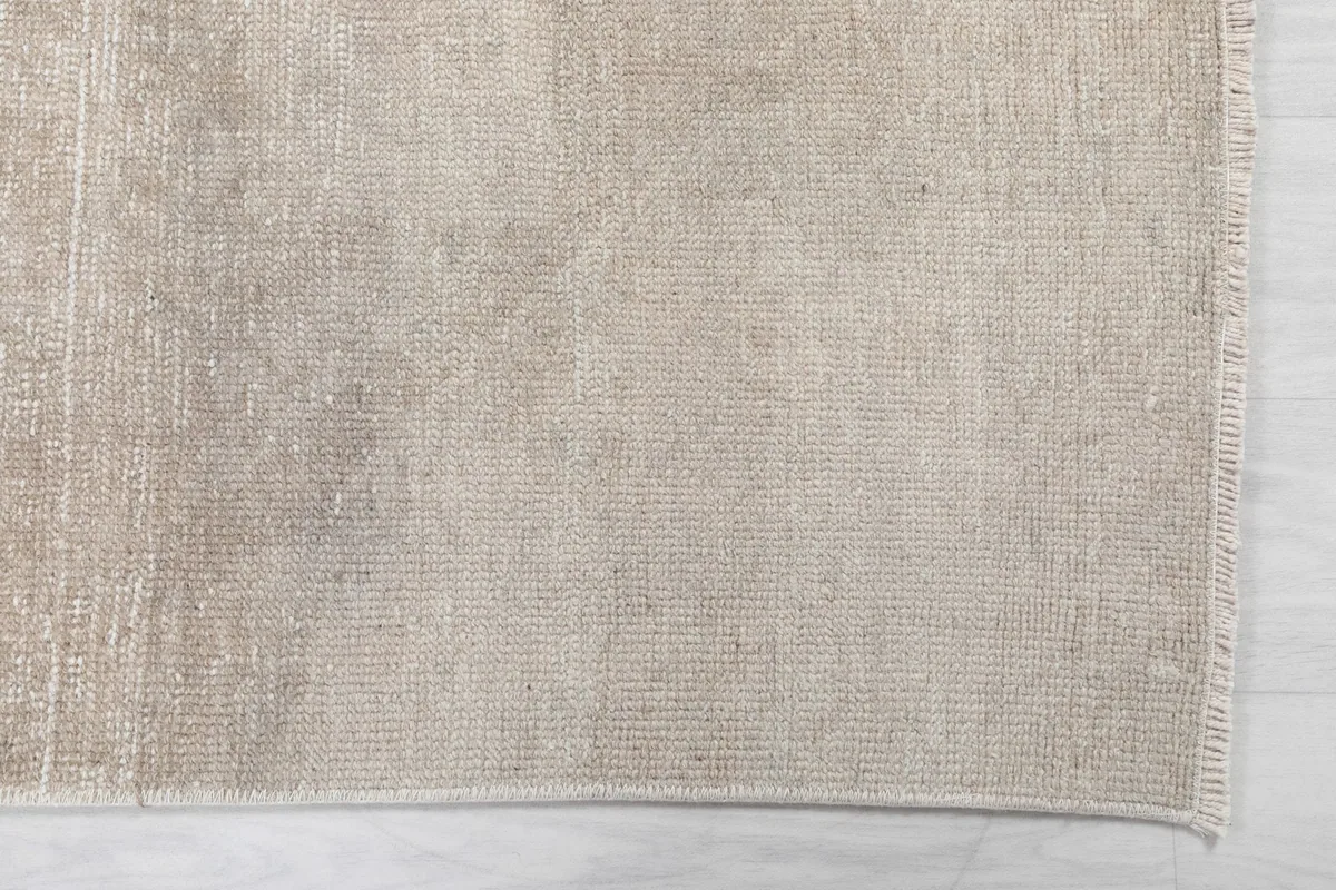 Overhead close-up showing the subtle geometric patterns and texture of the beige wool pile.
