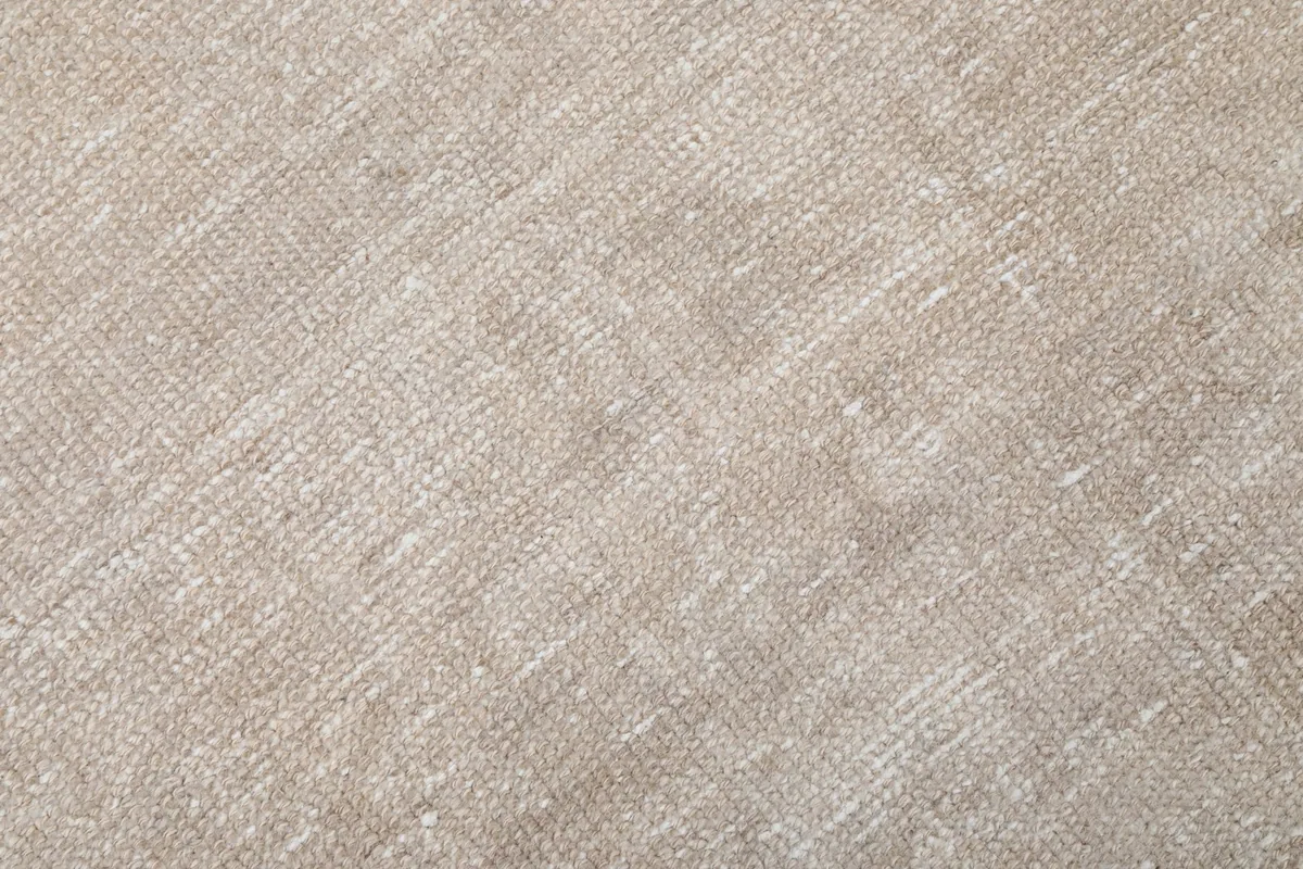 Close-up of the low wool pile, showing the hand-knotted texture and slight variations in beige color.