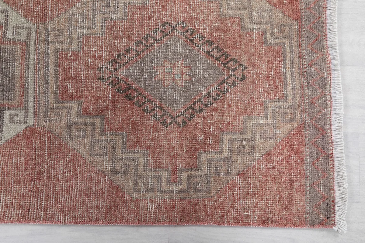 Detail view of a central geometric motif in gray and beige on the rust field