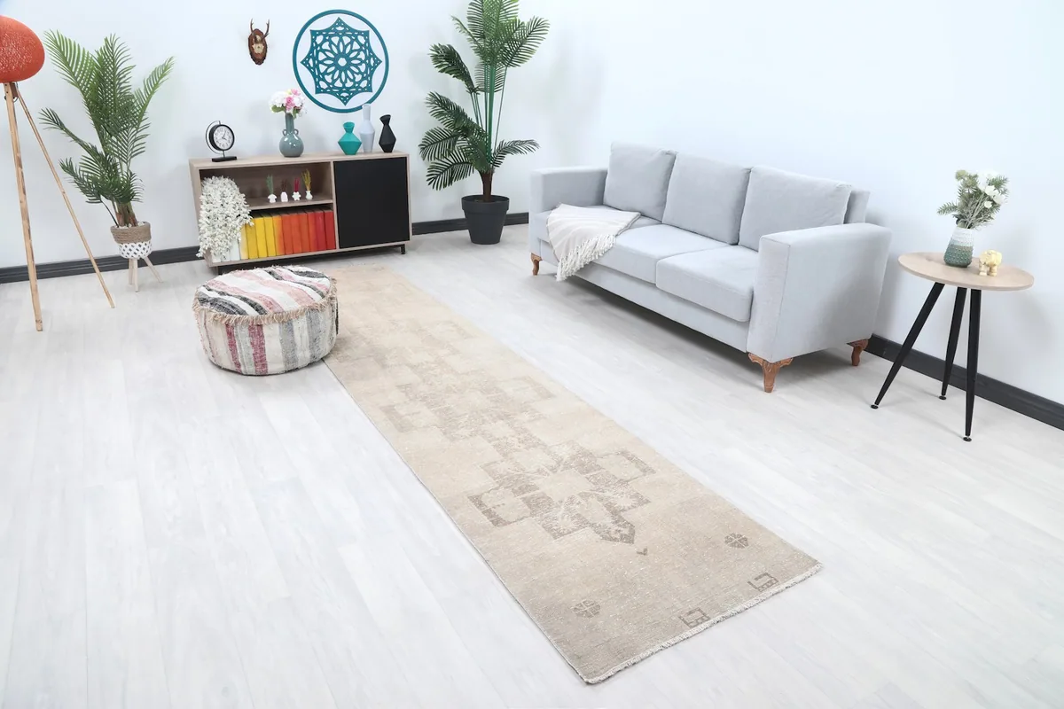 Angle view of the beige geometric runner rug in a room with a sofa and ottoman, highlighting its scale.