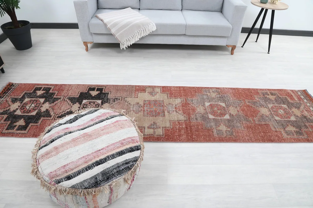Runner rug laid out in a room, providing a sense of scale with a sofa and ottoman.