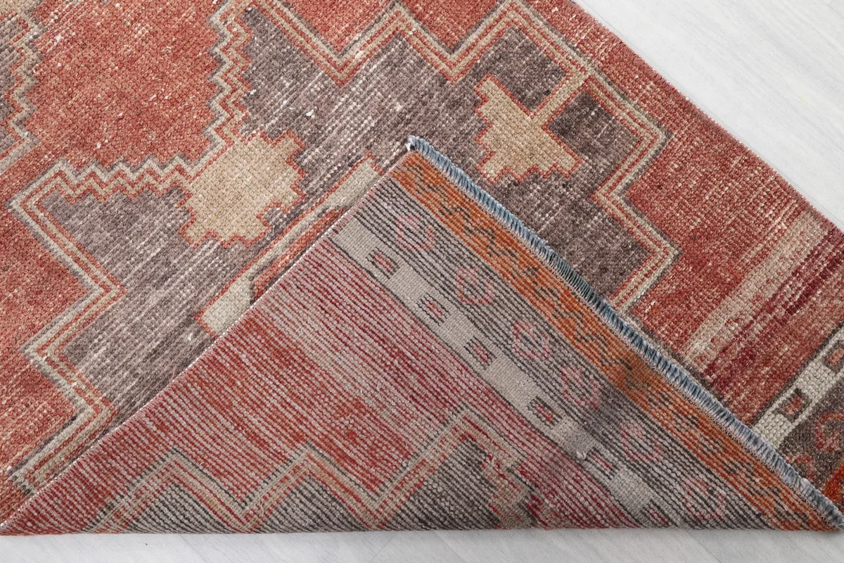 Folded corner of the rug revealing the cotton foundation and hand-knotted construction from the back.