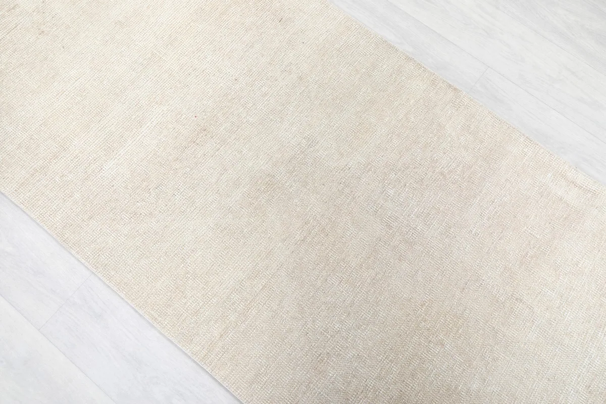 Overhead angle capturing the full length and uniform ivory tone of the runner rug
