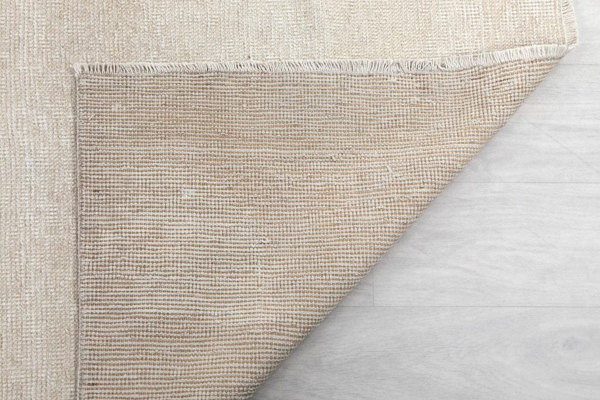 Folded corner of the rug showing the reverse side's tight weave and construction