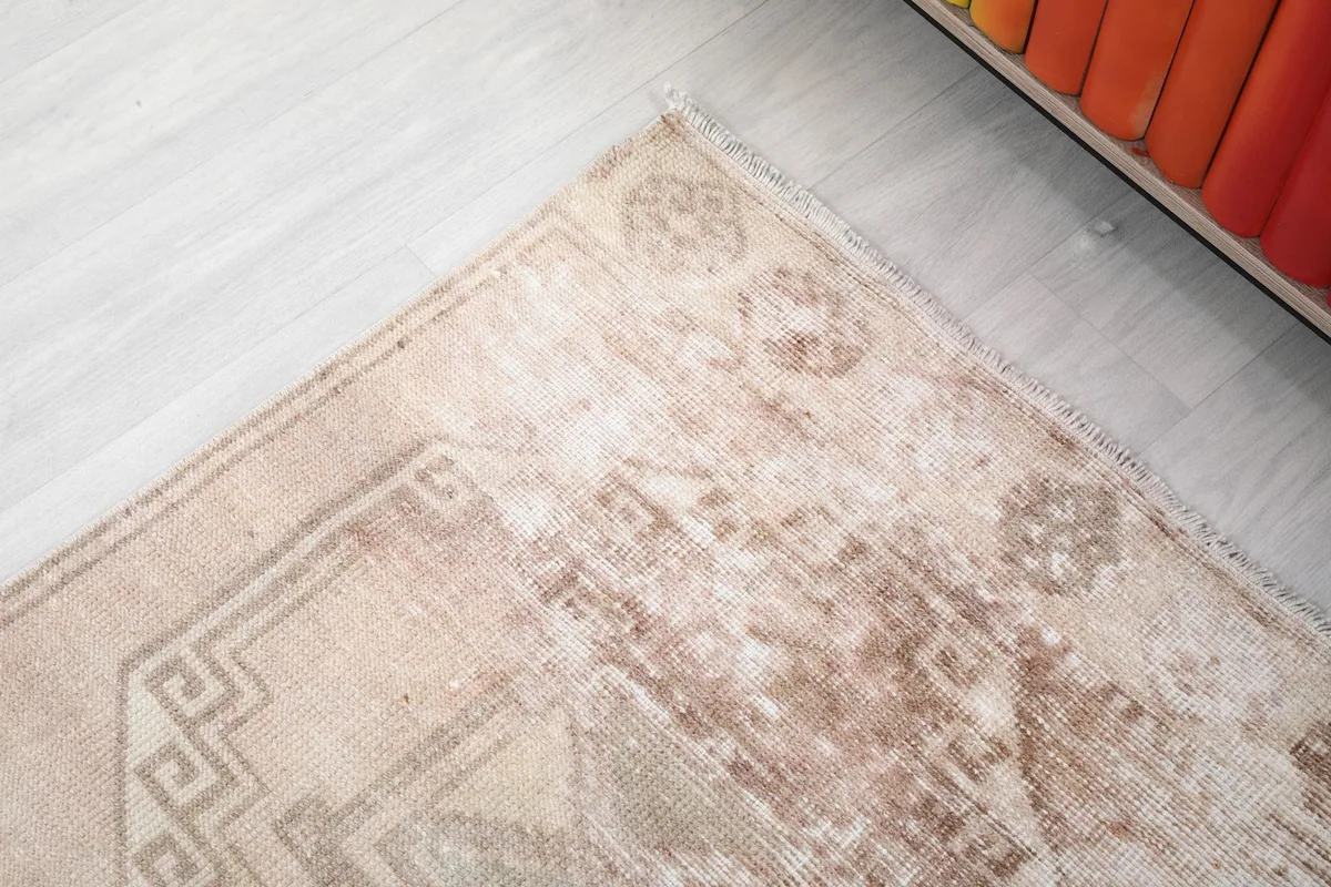 Corner detail of the rug, showing the distressed patina and the intricate geometric border.