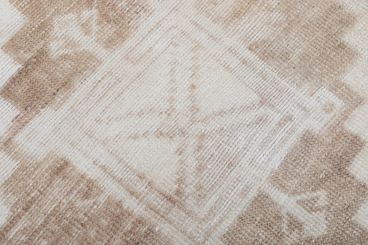 Close-up of the wool pile, showing the hand-knotted texture and faded beige and tan colors.