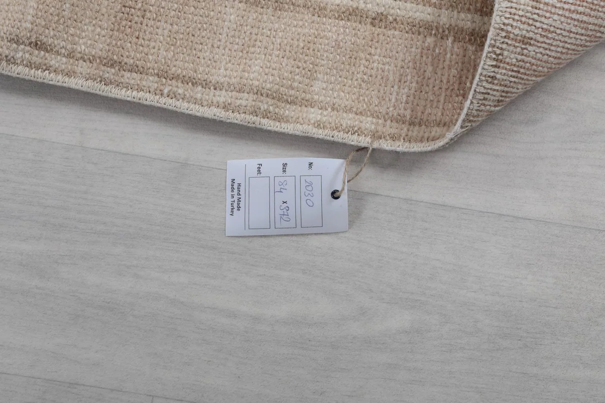 Product tag displaying the rug's size and origin, placed on the floor next to the rug.