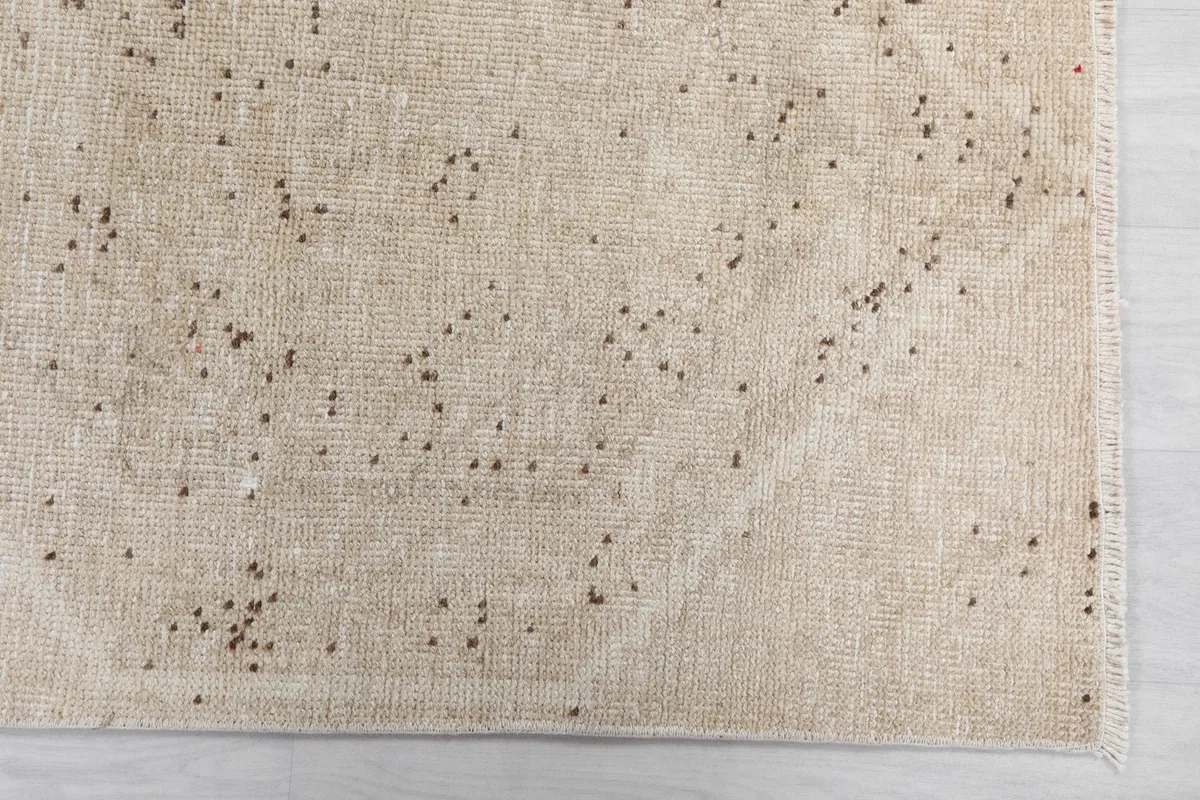 Close-up detail of the ivory rug's geometric pattern and subtle texture