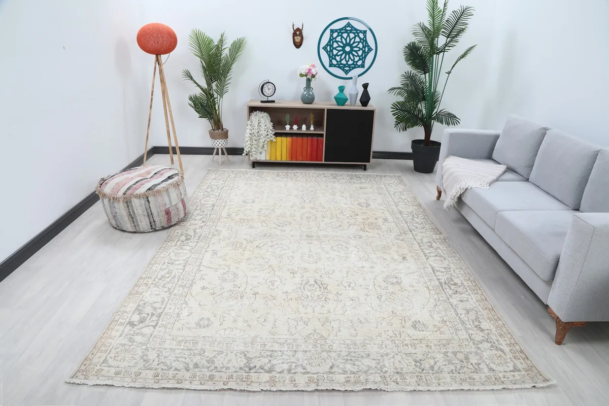 Large ivory and gray vintage rug placed in a modern living room setting