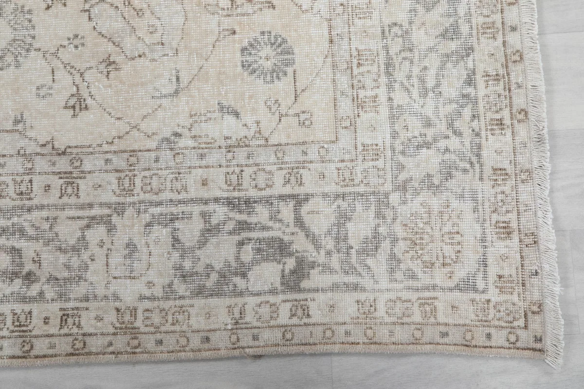 Detail of the rug's intricate gray and tan border pattern and corner