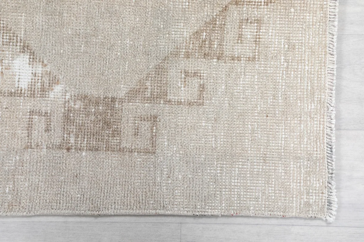 Detailed shot of the subtle tan geometric design and the edge of the vintage rug