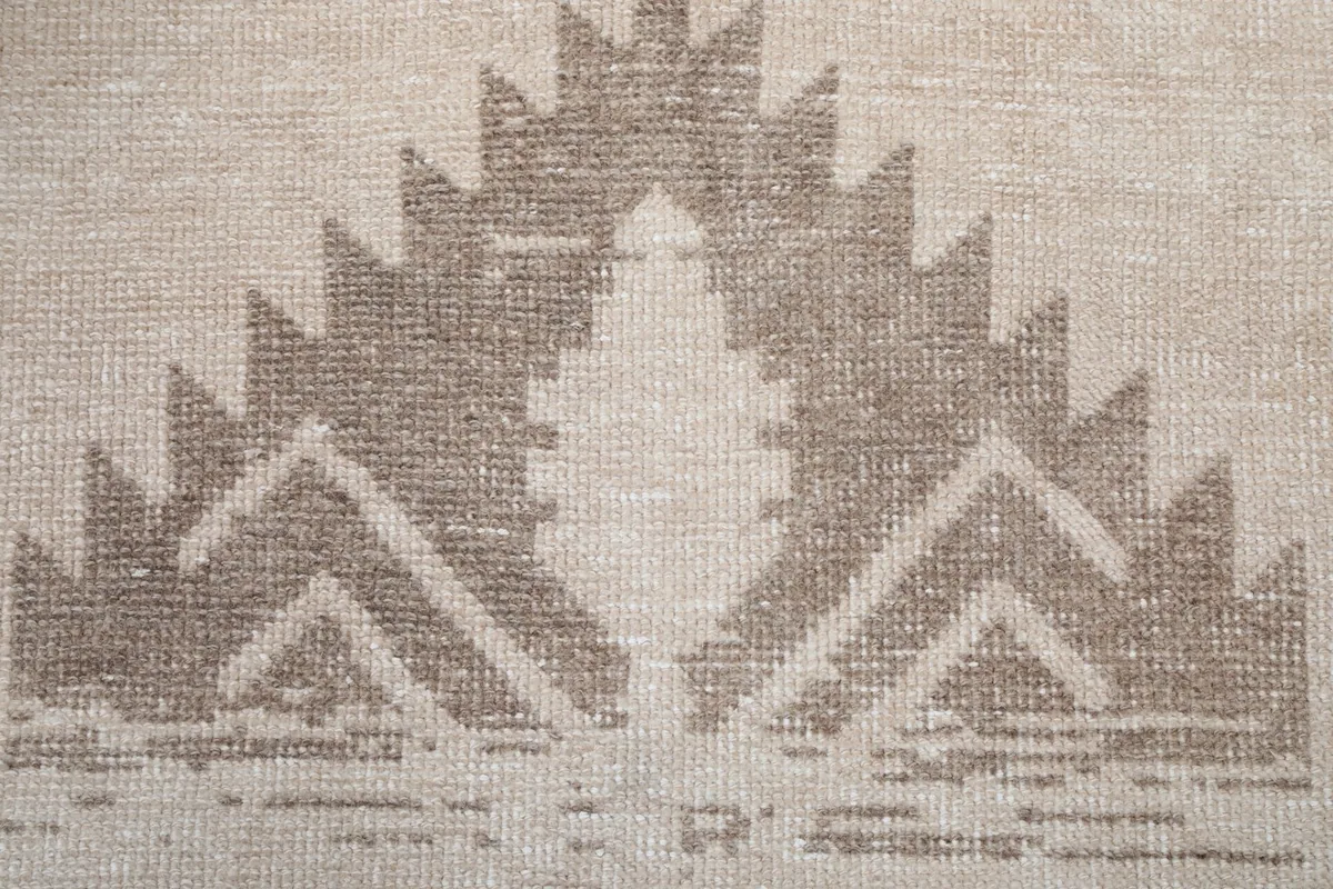 Close-up detail of the hand-knotted brown geometric motif, showing texture and weave