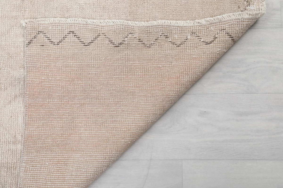 Underside view of the rug, revealing the tightly woven cotton foundation and short fringes