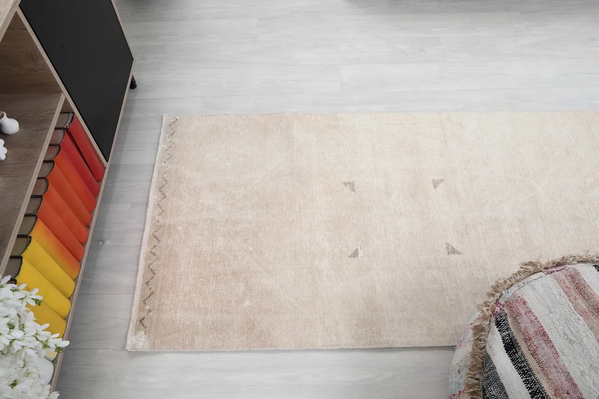 Overhead view of the rug's end, focusing on the muted tan colors and geometric accents