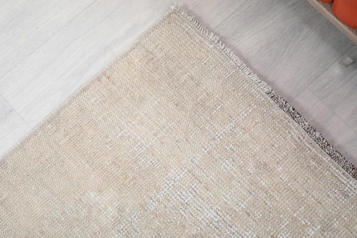 Close-up of the low wool pile and distressed surface of the cream and brown rug