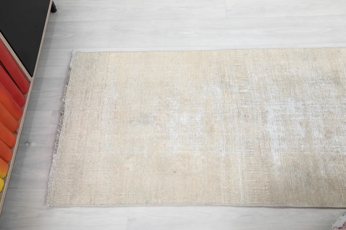 Overhead view of the distressed cream runner rug, highlighting its faded appearance