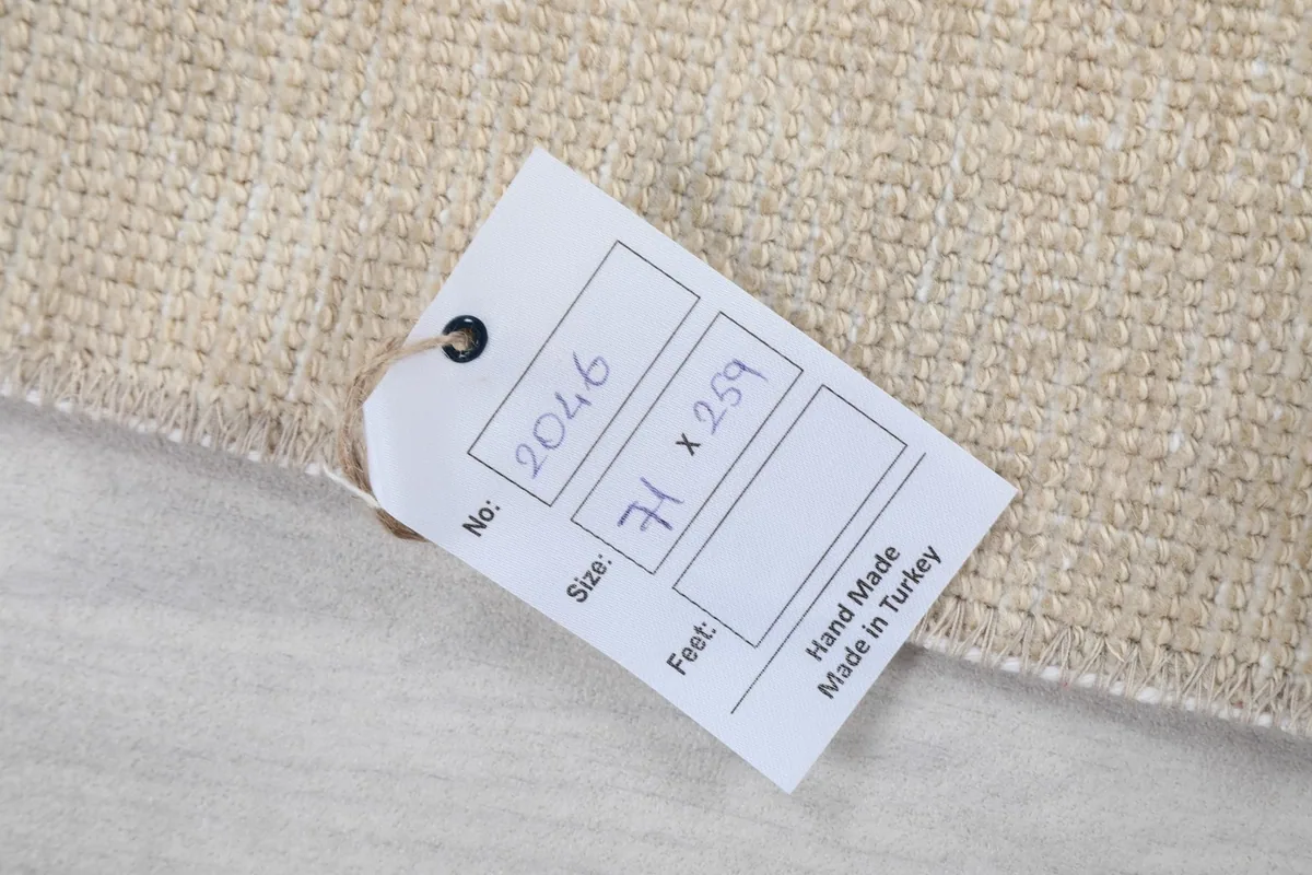 Product tag attached to the rug, displaying its unique number, size in cm, and origin