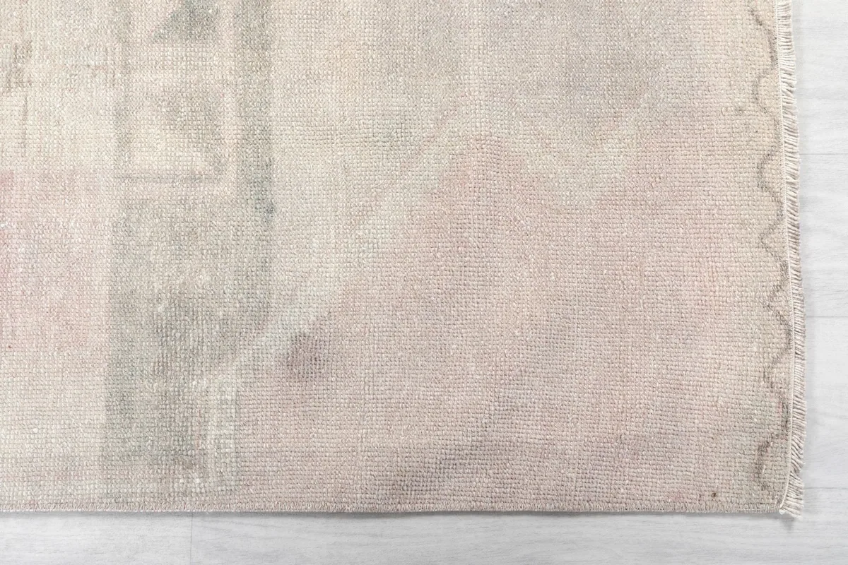 Detailed view of the rug's end, showing the subtle beige and rose colors and low pile