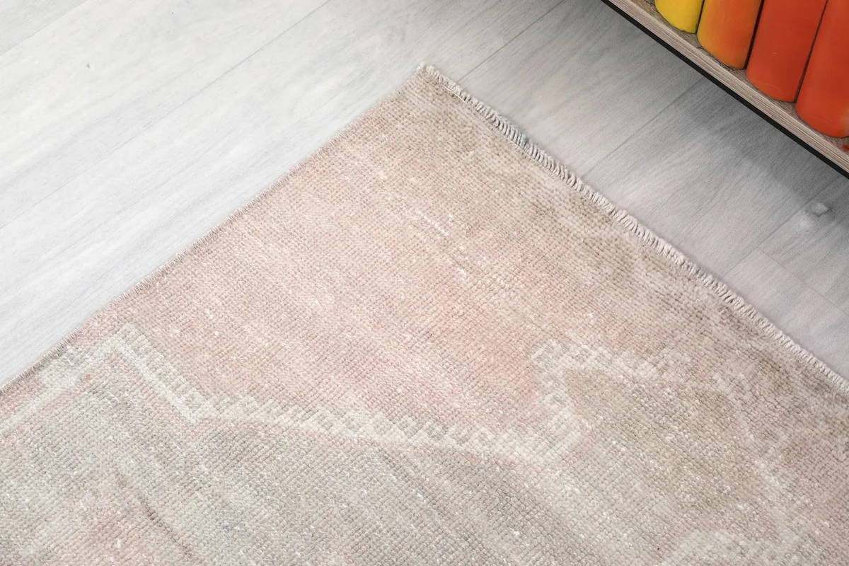 Corner detail of the rug, highlighting the subtle border and aged patina