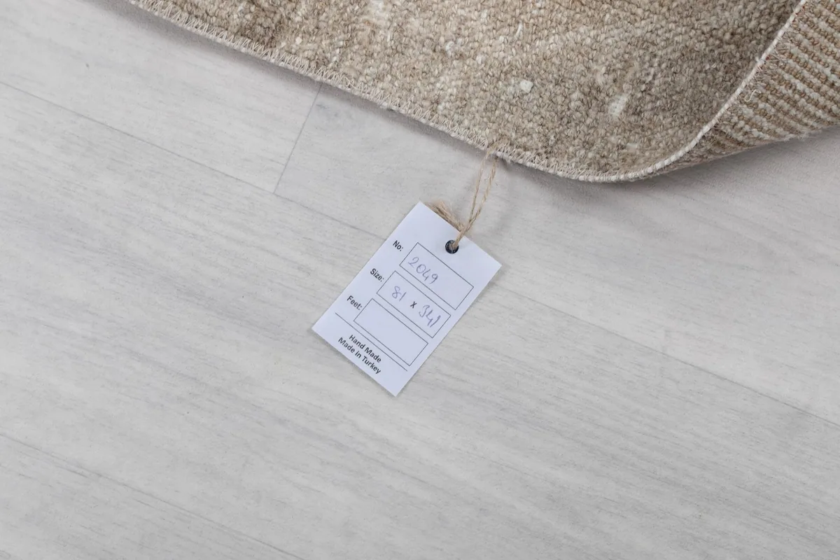 Product tag showing the rug's size and origin, lying on the floor next to the rug.