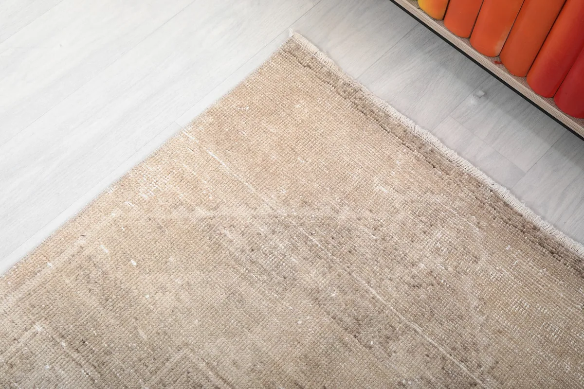 Corner detail of the rug, showing the worn edges and subtle color shifts inherent to its vintage character