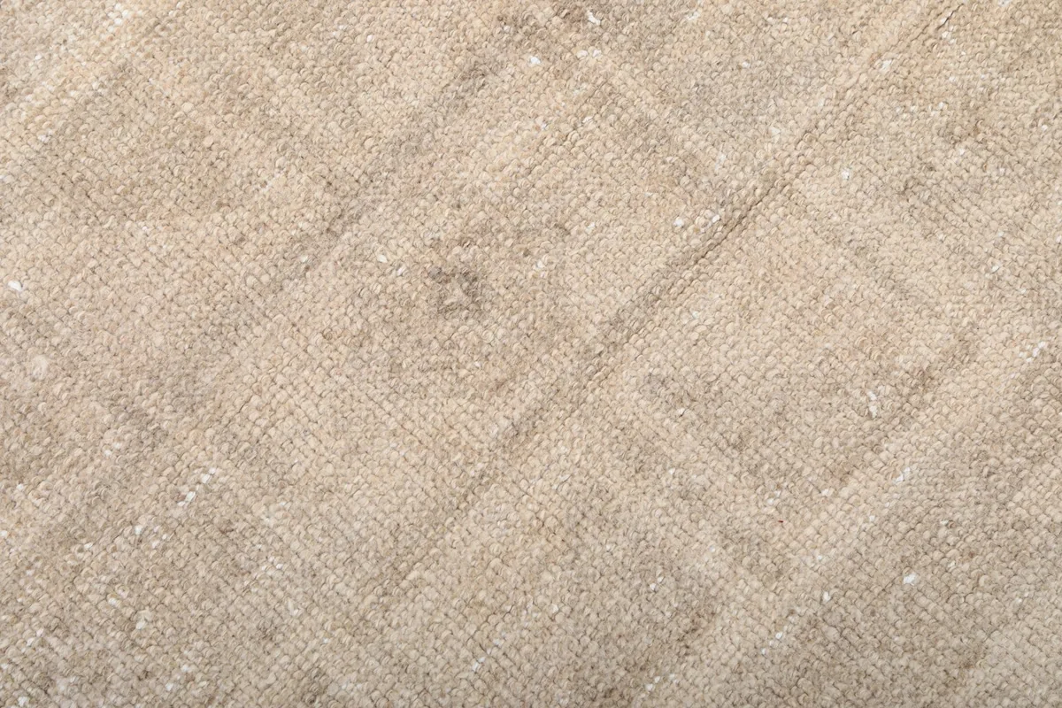 Very close view of the low wool pile and hand-knotted texture of the vintage tan rug