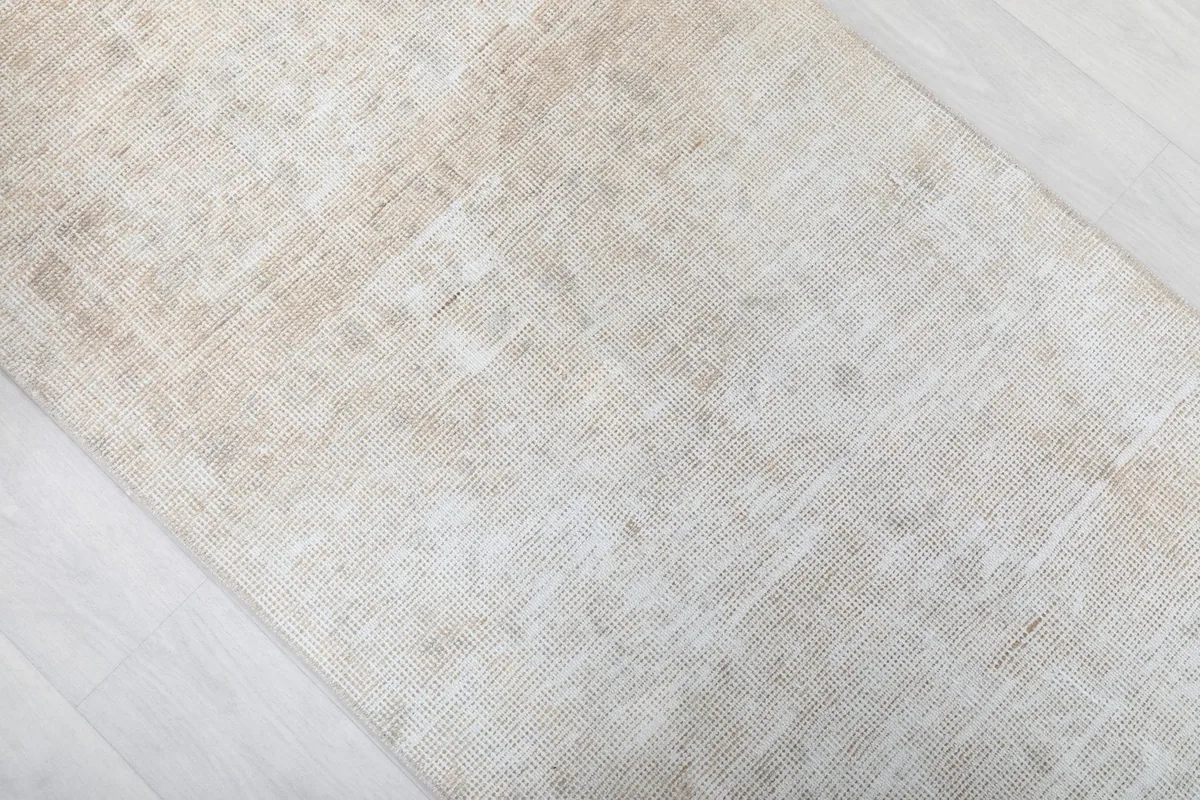 Angled view highlighting the distressed look and varying beige shades of the rug surface