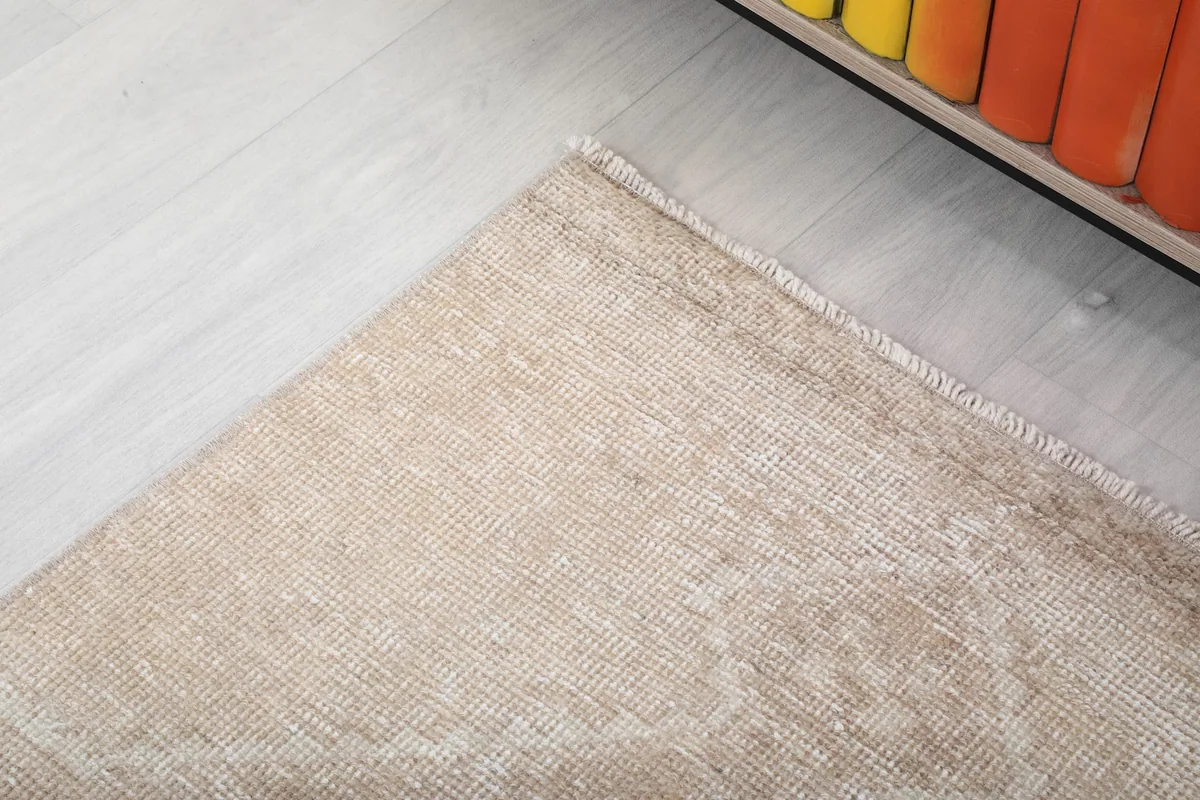 Corner detail of the rug showing the subtle border and edge finish next to a cabinet