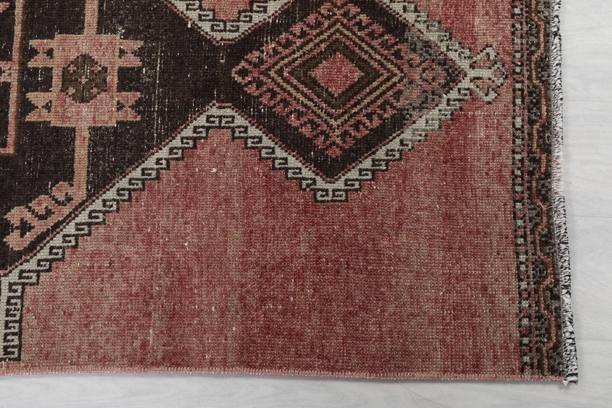 Detailed view of the rose field and charcoal geometric patterns with patina