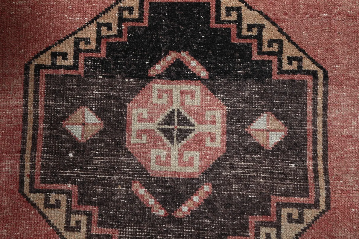 Intricate detail of a tribal medallion, showcasing the black, rust, and beige tones.