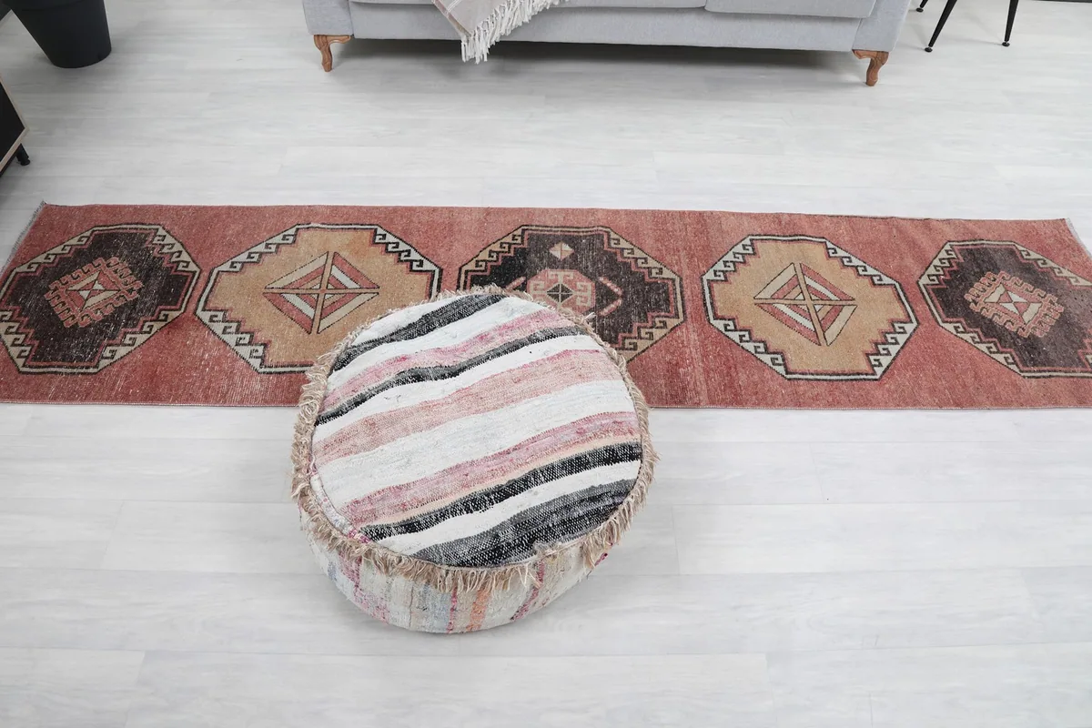 Overhead view of the rug's full length, with a pouf in the foreground.