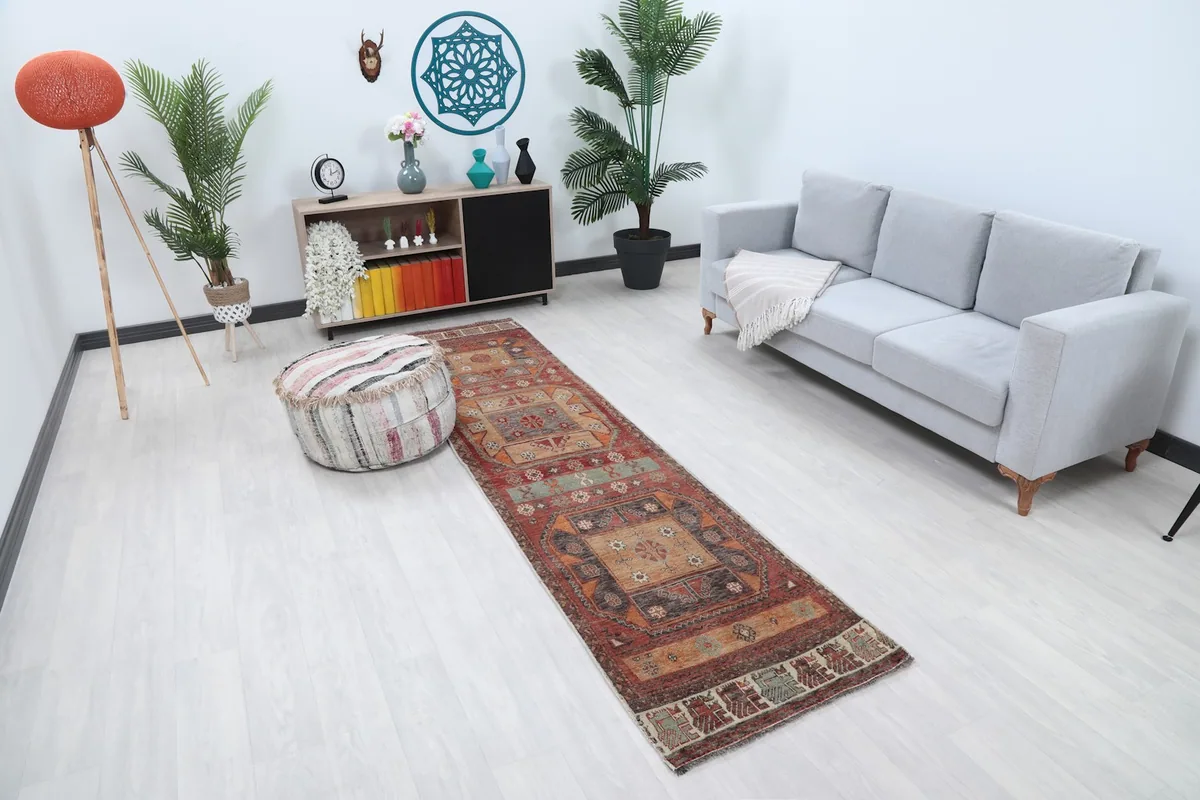 Long view of the rust and beige tribal runner rug extending through a hallway, next to a striped pouf