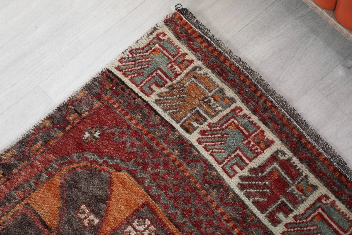 Corner detail of the rug's border, displaying intricate tribal motifs and fringe