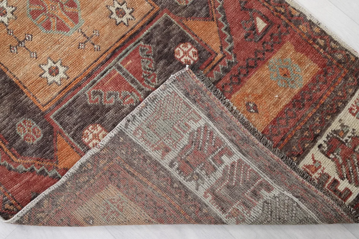 View of the back of the hand-knotted wool rug, showing a folded corner revealing the cotton foundation