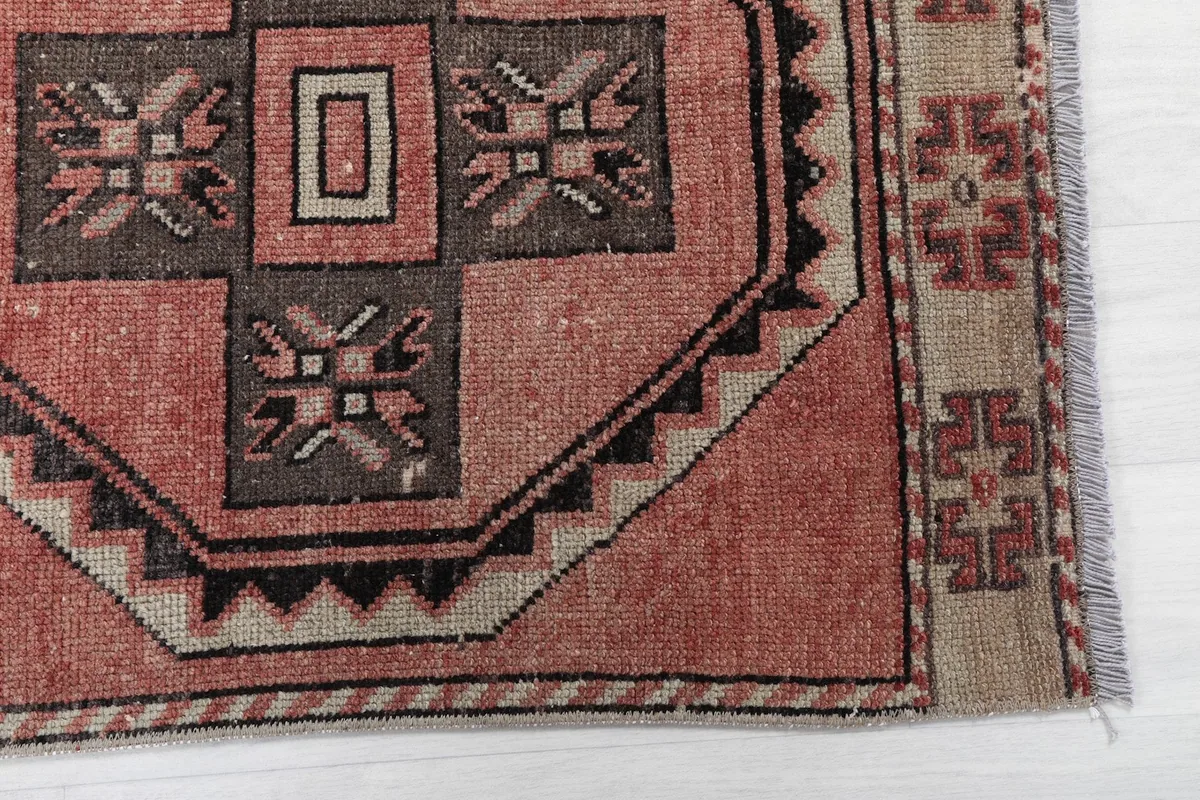 Detailed view of the rug's border and a geometric medallion with rust and black tones