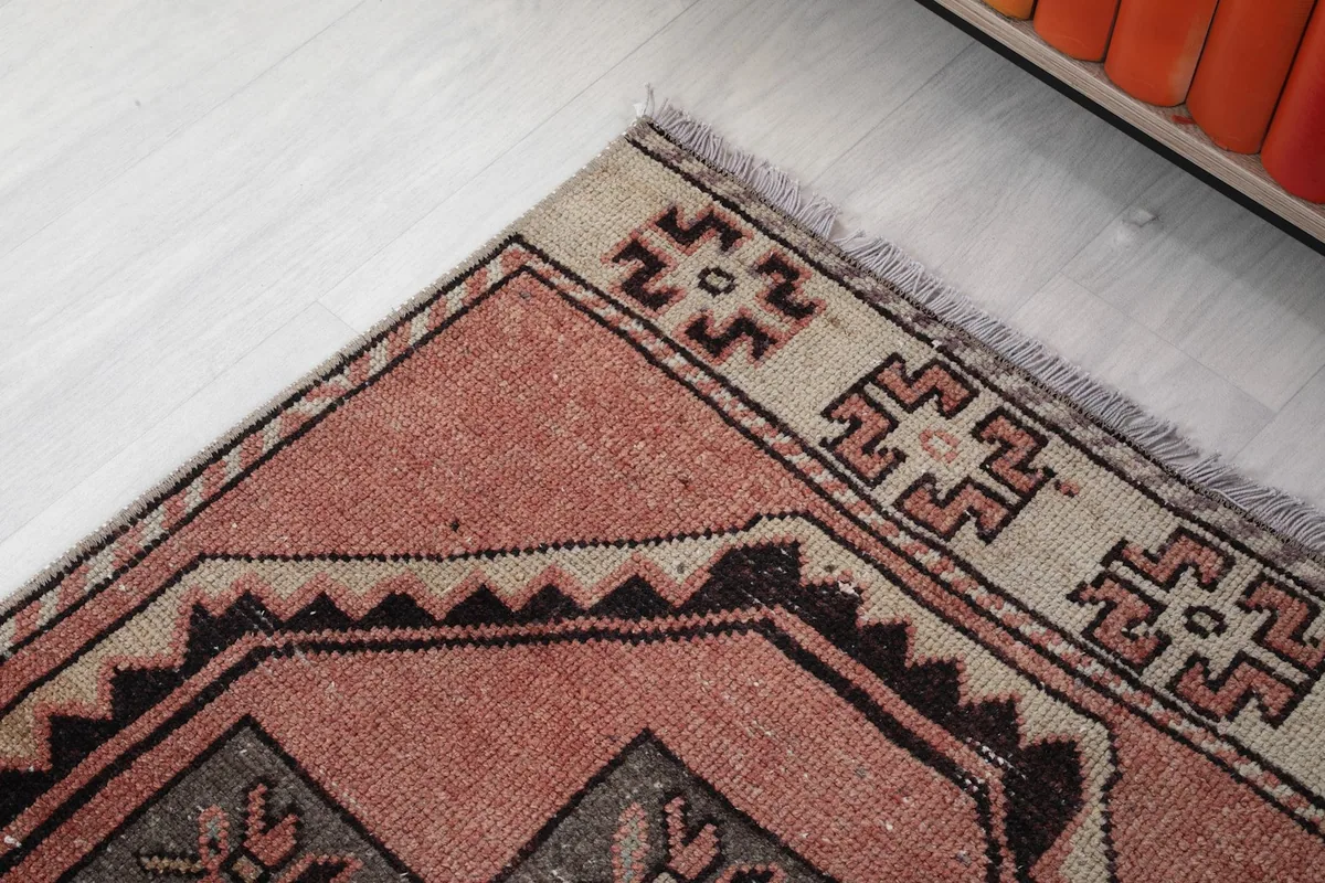 Detail of the rug's top border and corner, showing the beige and black geometric motifs