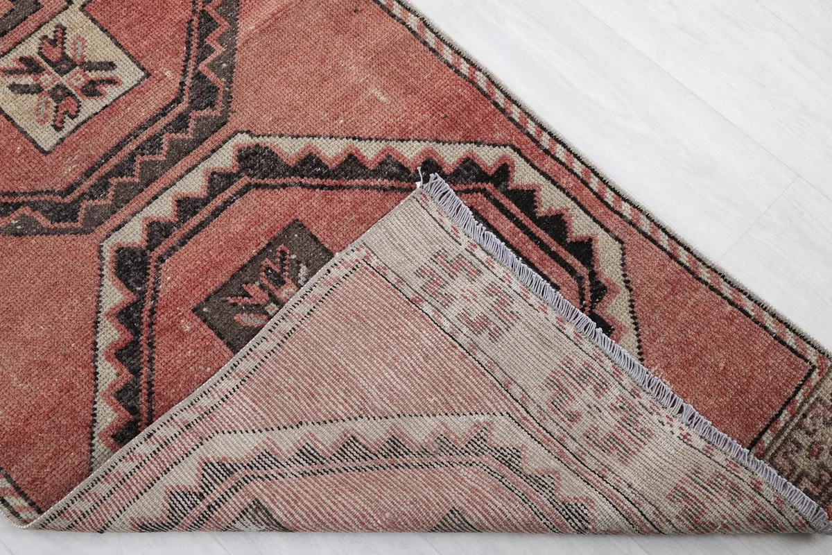Corner of the rug folded back to reveal the cotton foundation and hand-knotted construction