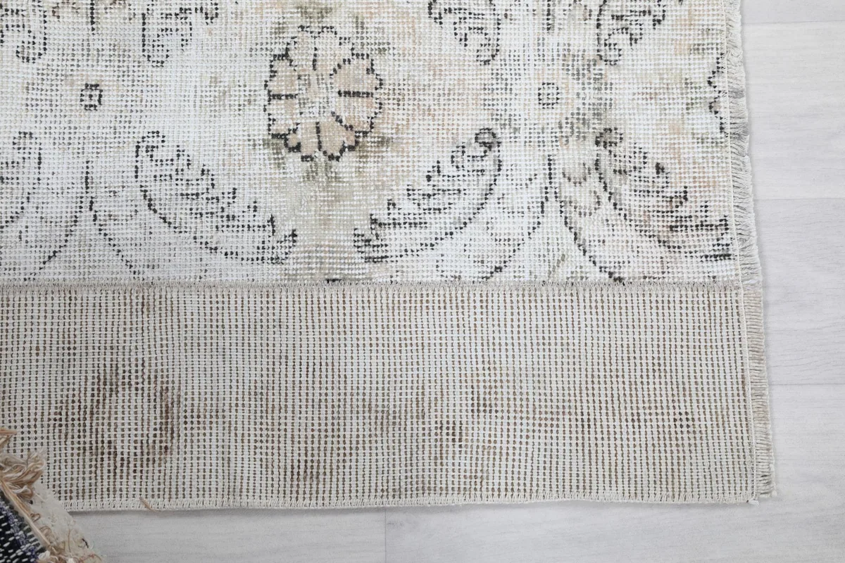 Detailed view of the rug's cream field and gray medallion pattern, showing the wool pile and cotton foundation.