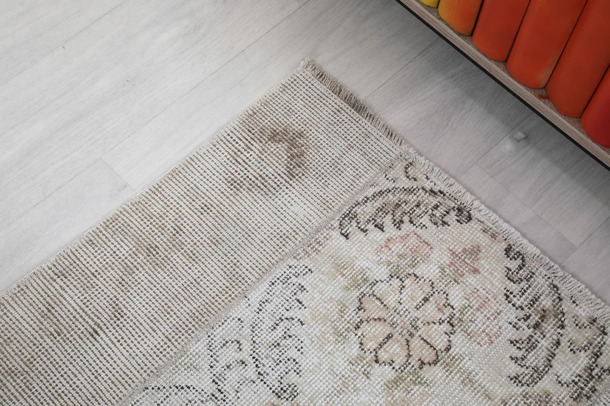 Close-up of the rug's border area, showing the transition from the patterned field to the solid beige edge.