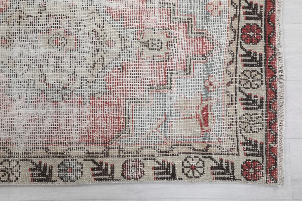 Detailed view of the rug's faded rose and beige field with geometric motifs and border