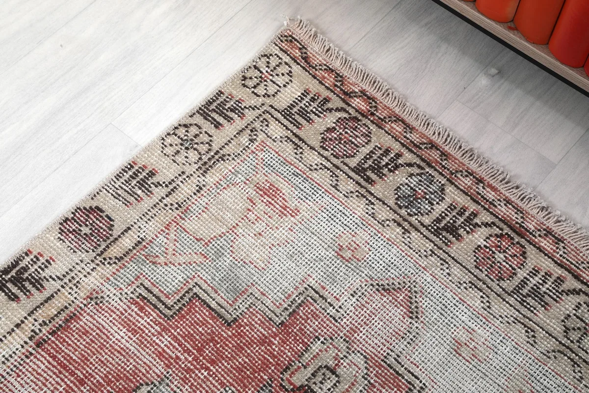 Corner detail of the rug showing the border design and muted color variations
