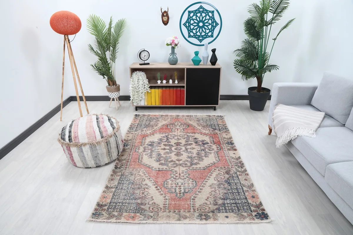 Full view of the ivory, rust, and blue vintage rug placed in a modern living room setting