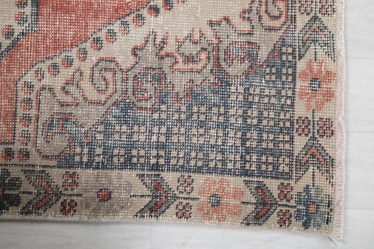 Detailed view of the blue geometric corner pattern and floral motifs on the vintage rug