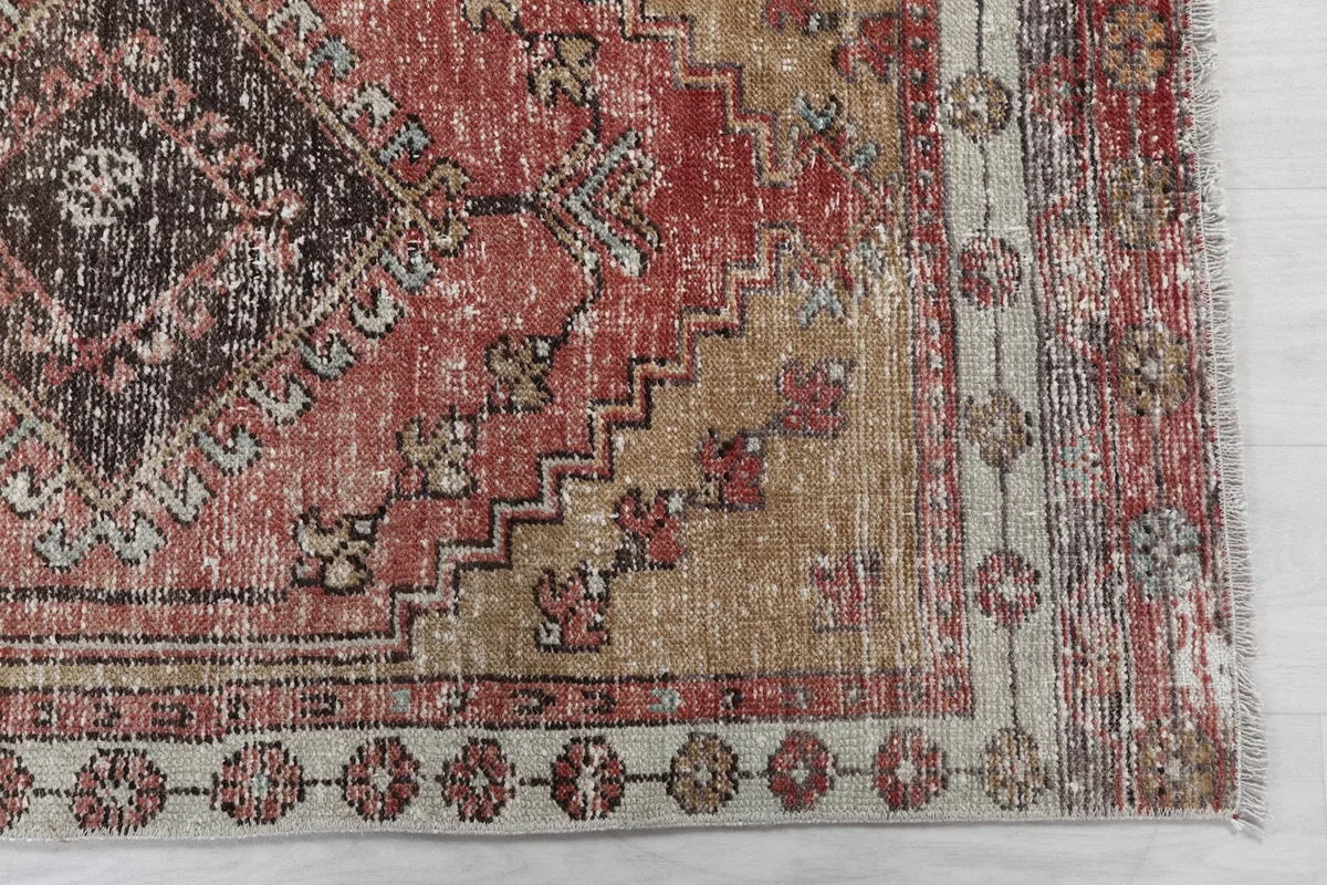 Detailed view of the rug's geometric pattern in rust and beige, showing areas of wear and patina.